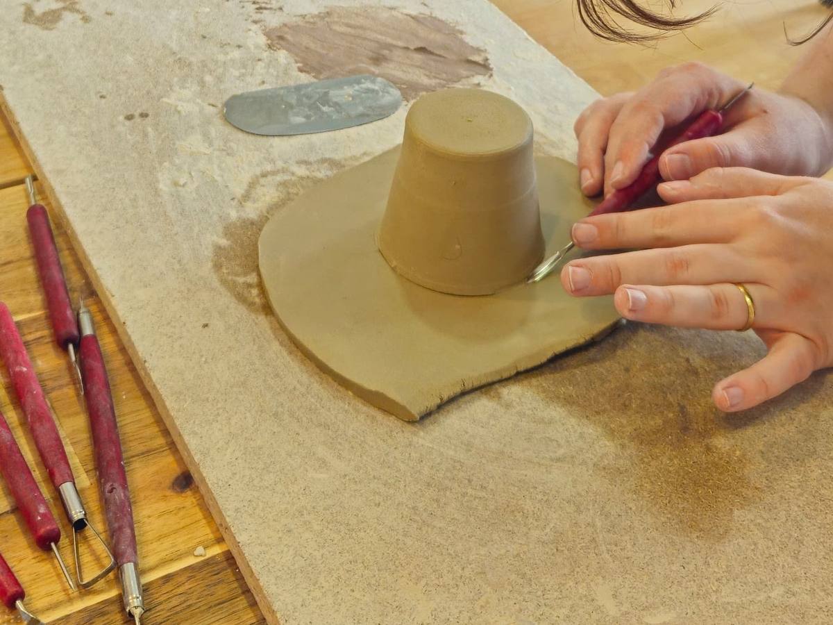 Mãos a esculpir um modelo de gesso sobre a bancada