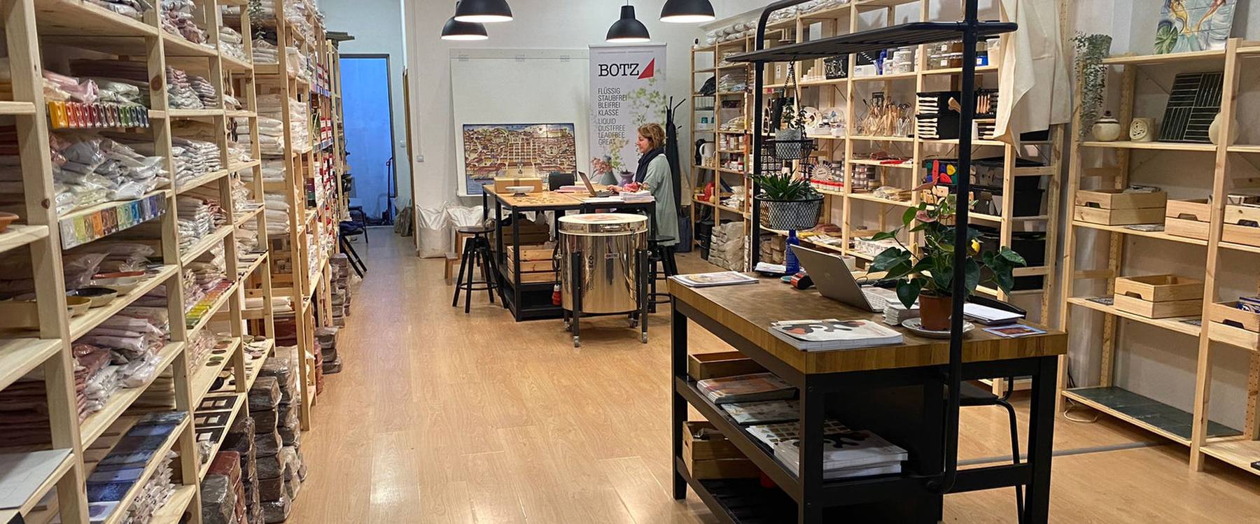 Interior da loja da Ceramista Shop no Porto, com estantes de materiais e bancadas