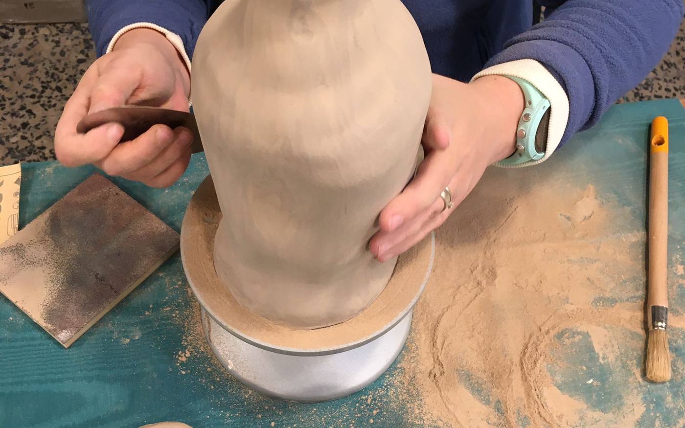 Aluna a levantar uma peça à mão, num workshop de iniciação da Ceramista Shop