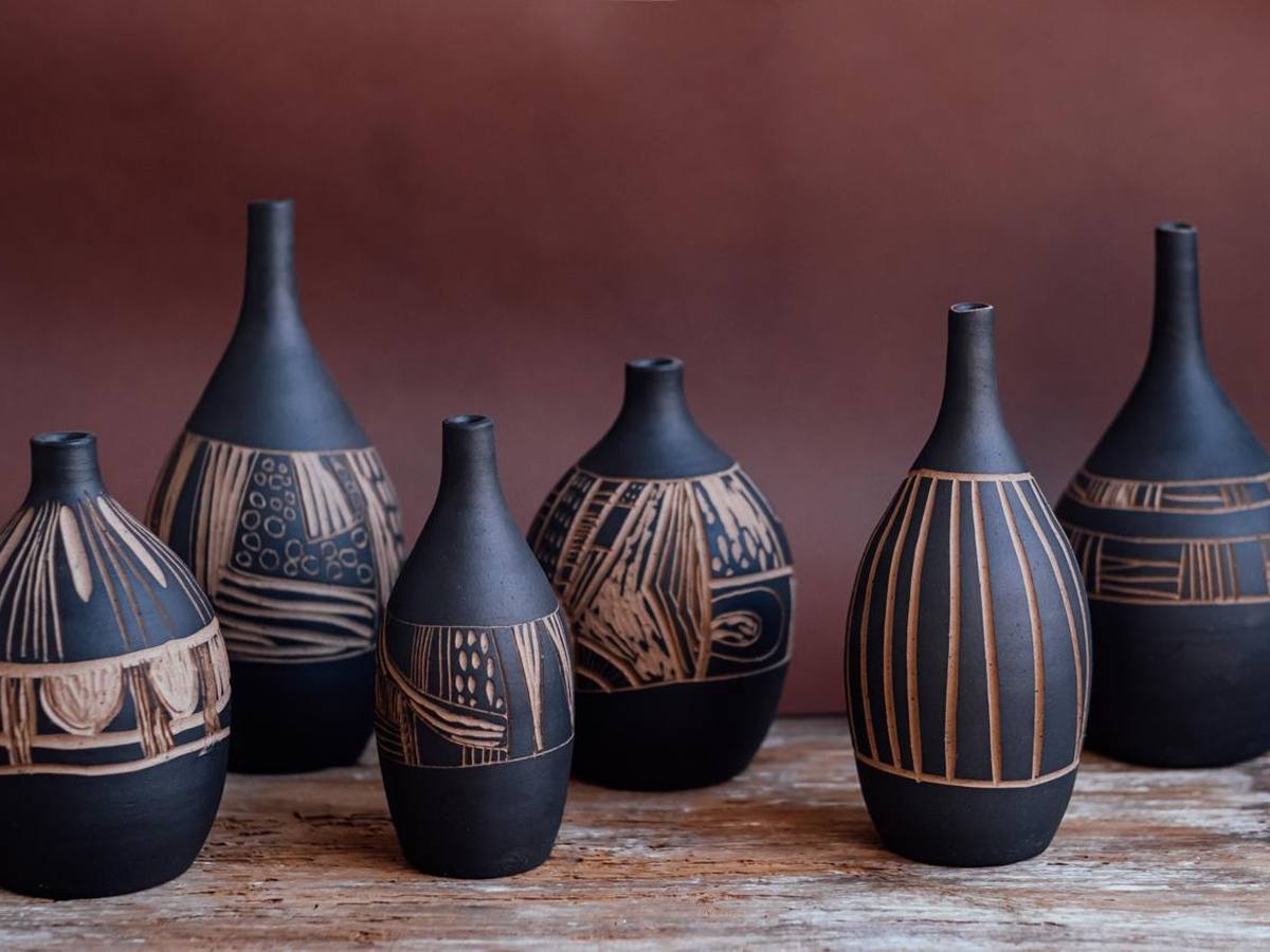 Garrafas de grés preto com esgrafito, alinhadas sobre madeira
